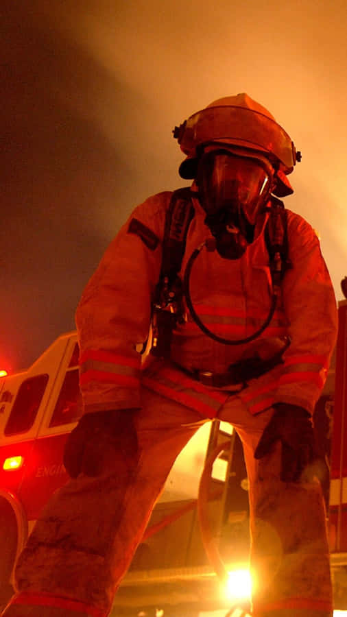 A Firefighter Standing In Front Of A Fire Truck Wallpaper