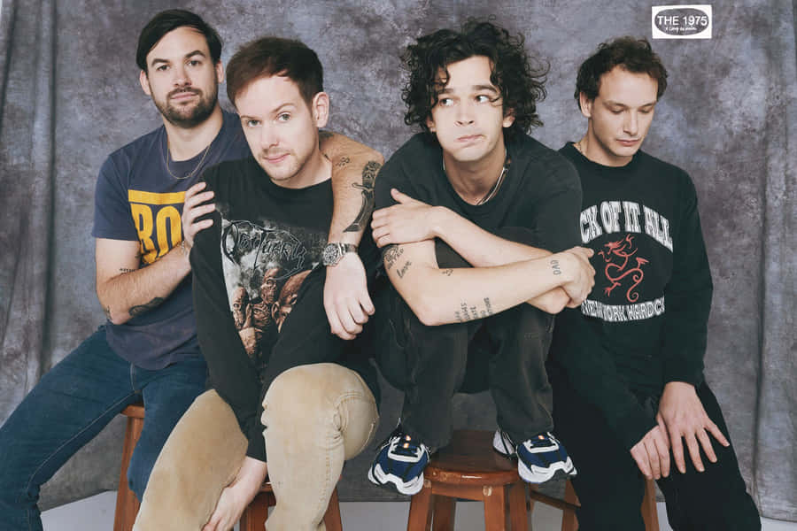 A Group Of Men Sitting On Stools Wallpaper