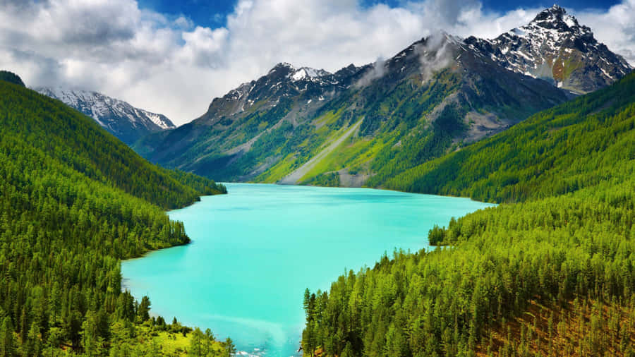 A Lake Surrounded By Trees And Mountains Wallpaper