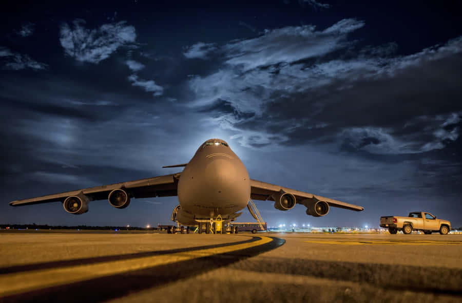 A Large Military Aircraft On The Runway At Night Wallpaper