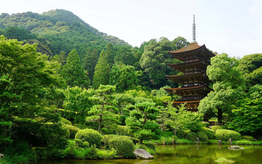 A Pagoda Tower In A Garden With Trees And Bushes Wallpaper