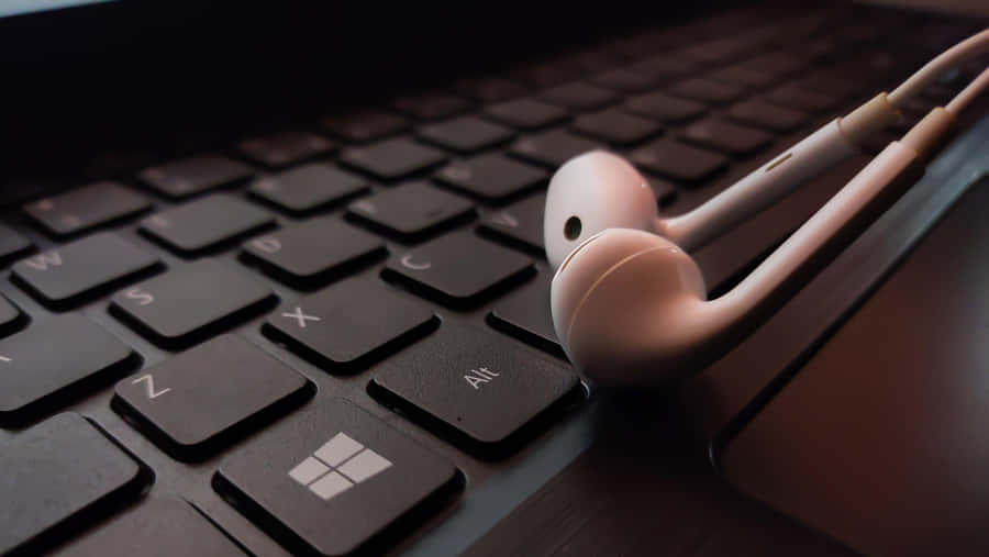 A Pair Of Headphones On A Laptop Keyboard Wallpaper