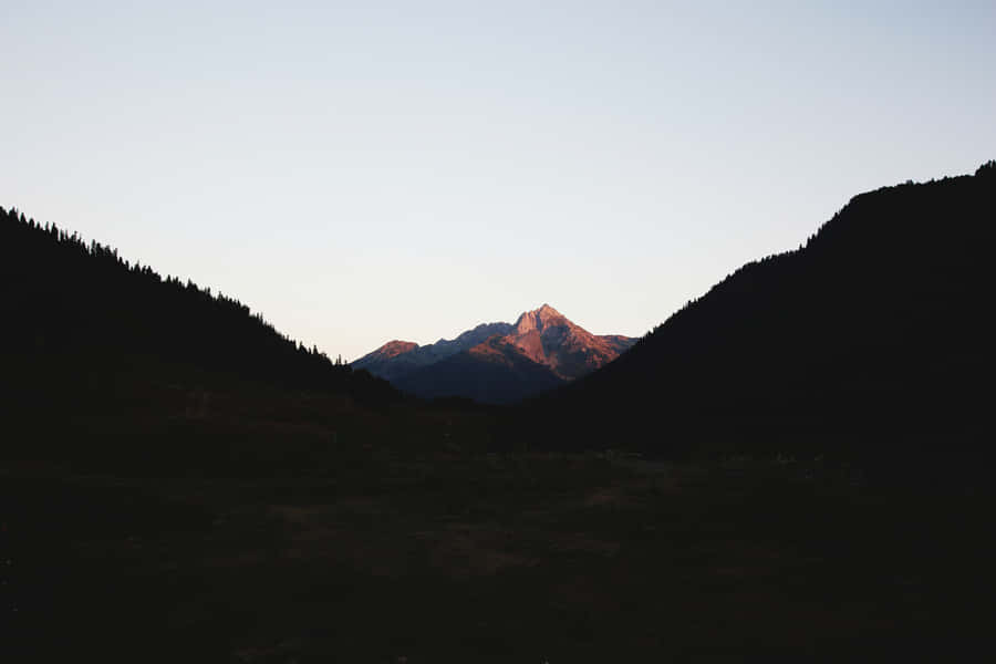 A Peaceful Vista Of A Minimalist Mountain Rises Into A Beautiful Blue Sky Wallpaper