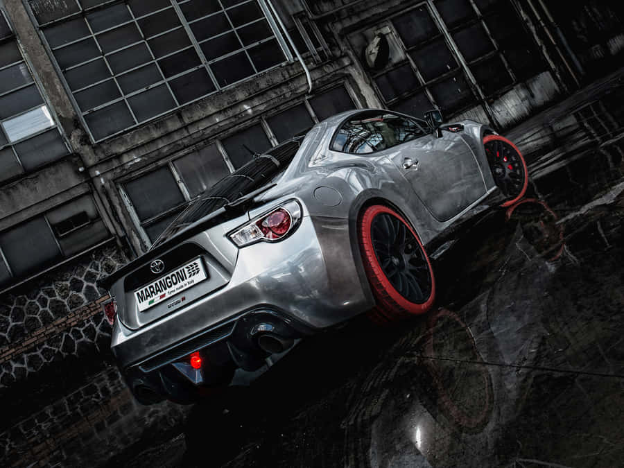 A Silver Sports Car Is Parked In A Rainy Street Wallpaper