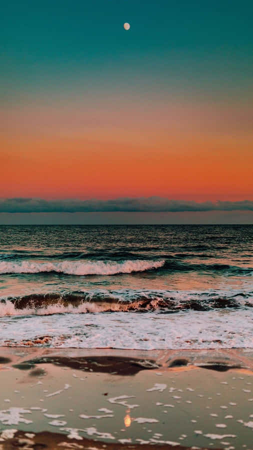 A Sunset On The Beach With The Moon Reflecting In The Water Wallpaper