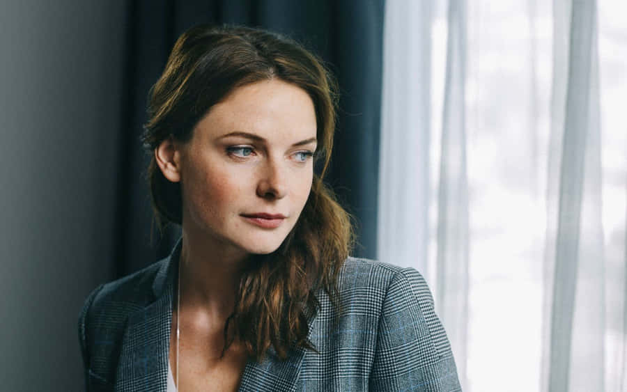 A Woman In A Gray Suit Looking Out The Window Wallpaper