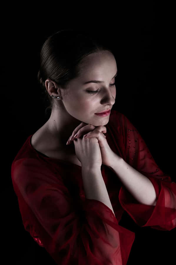 Devout Woman In Red Dress Engaging In Solitary Prayer Wallpaper