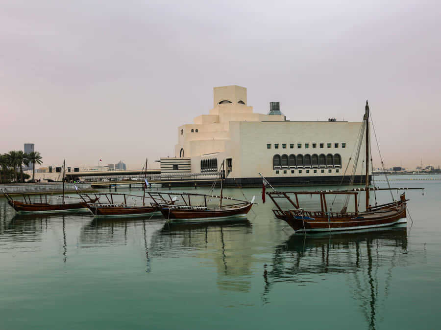 Majestic View Of The Museum Of Islamic Art With Serene Boats In The Forefront, Doha, Qatar. Wallpaper