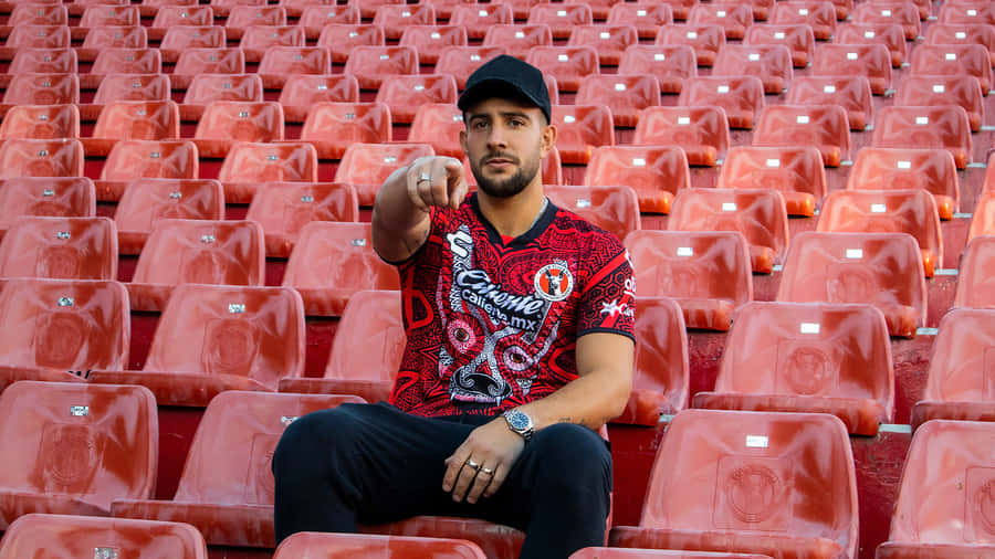 Man Pointingin Stadium Seats Wallpaper