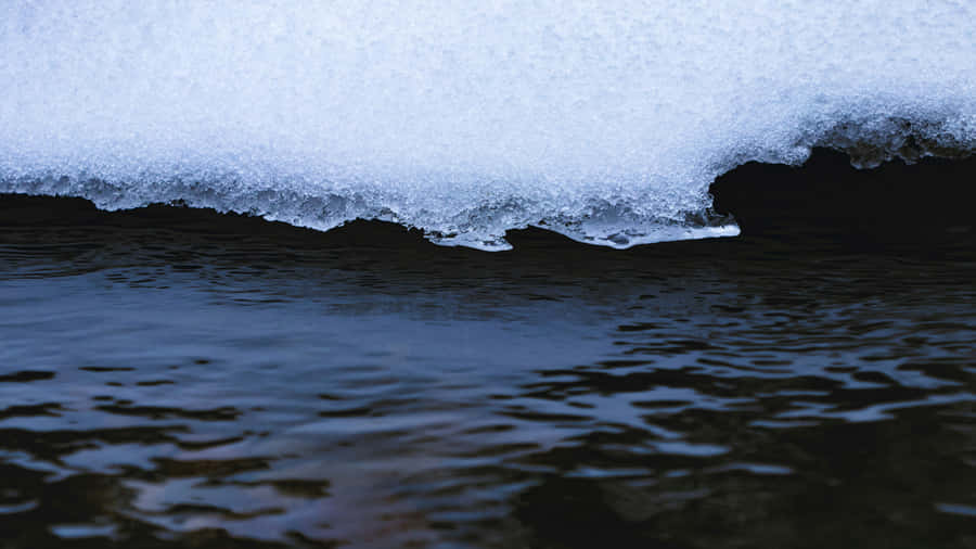 Melting Snow Edge Over Dark Water.jpg Wallpaper