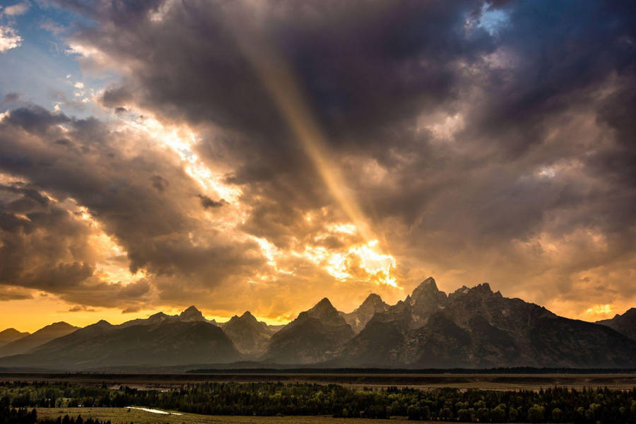 Rocky Mountain With Setting Sun And Clouds Wallpaper