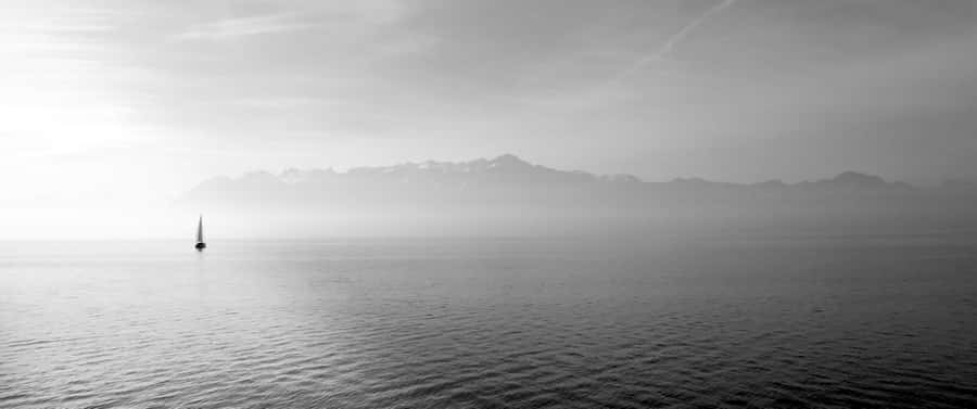 Solitary_ Sailboat_ Against_ Mountain_ Backdrop Wallpaper