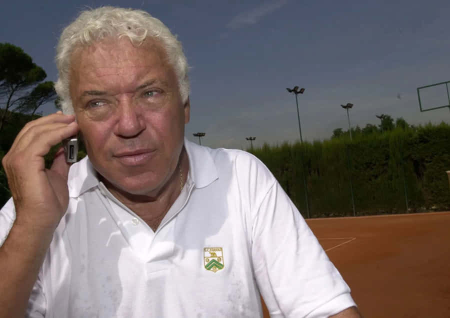 Tennis Veteran On Phone Courtside Wallpaper