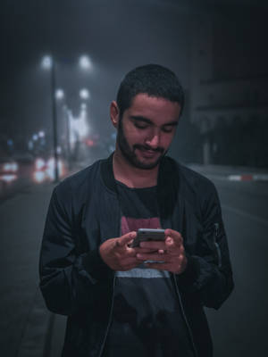 4k Black Hair Man Holding Phone Wallpaper