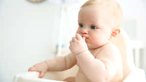 A Baby Is Sitting In A White High Chair Wallpaper