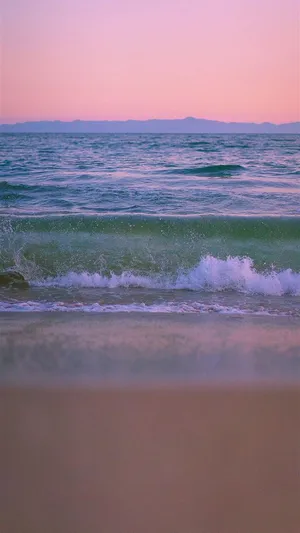 A Beach With Waves And A Sunset Wallpaper