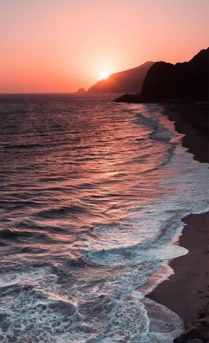 A Beach With Waves And A Sunset Wallpaper