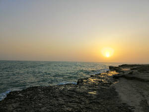 A Beautiful Sunset At A Rocky Beach. Wallpaper