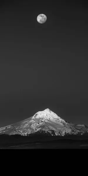 A Black And White Photo Of A Mountain With A Moon In The Sky Wallpaper