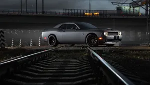 A Black Car Is Driving Down The Tracks At Night Wallpaper