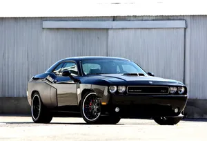 A Black Dodge Challenger Parked In Front Of A Building Wallpaper