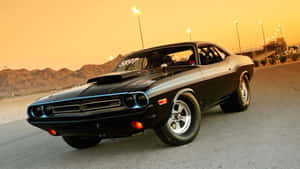 A Black Muscle Car Driving Down A Desert Road Wallpaper