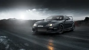 A Black Sports Car Driving On A Road Wallpaper