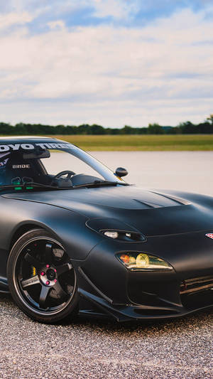 A Black Sports Car Is Parked On A Road Wallpaper