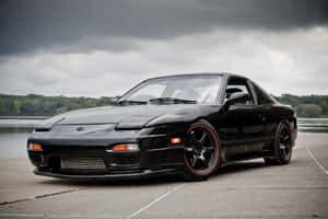 A Black Sports Car Parked In Front Of A Lake Wallpaper