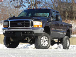 A Black Truck Is Parked In The Snow Wallpaper