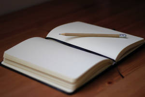 A Blank Page From A Thick Notebook With A Pencil On Top Wallpaper