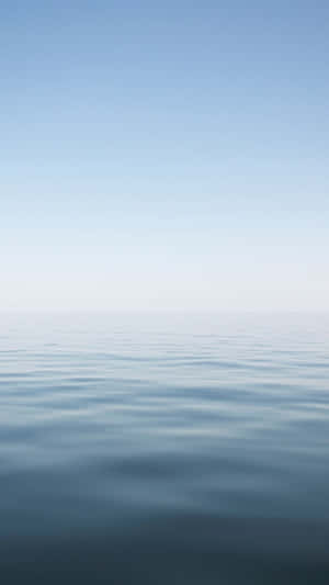 A Blue Ocean With A White Sky Wallpaper