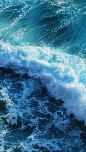 A Blue Ocean With Waves Crashing Over It Wallpaper