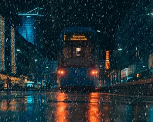 A Blue Tram Driving Down A City Street At Night Wallpaper