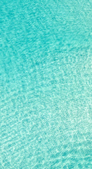 A Blue Water Surface With A White Sand Beach Wallpaper