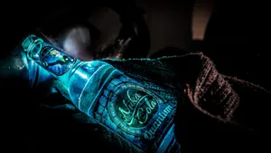 A Bottle Of Vodka Is Lit Up In The Dark Wallpaper