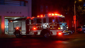 A Brave Firefighter Ready For Rescue With A Firetruck Wallpaper