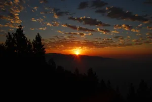 A Breathtaking Sunrise, Illuminating The Stunning Forest And Mountain Range. Wallpaper