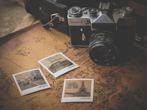 A Camera And A Map With Photos On It Wallpaper