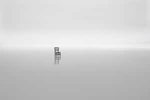 A Chair Sits On A Solitary Island In The Middle Of The Ocean Wallpaper