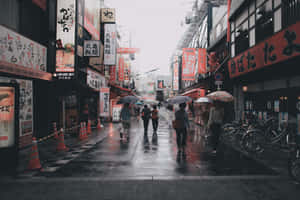 A City Street With People Walking With Umbrellas Wallpaper