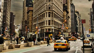 A City Street With Tall Buildings And Taxis Wallpaper