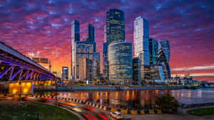 A Cityscape With A Bridge And Skyscrapers At Sunset Wallpaper