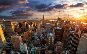 A Cityscape With Buildings And Clouds At Sunset Wallpaper