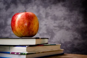 A Colorful Collection Of Books With A Single Apple Popping Against The Background. Wallpaper