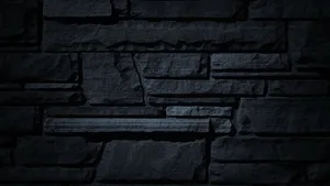 A Dark Gray Stone Wall Perfectly Blending With The Surrounding Landscape. Wallpaper
