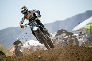 A Dirt Bike Rider Is Riding His Bike On A Dirt Track Wallpaper