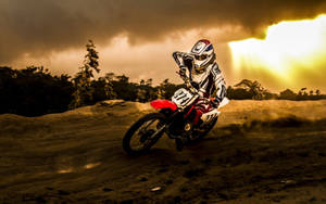 A Dirt Bike Rider Is Riding His Bike Through A Dirt Field Wallpaper