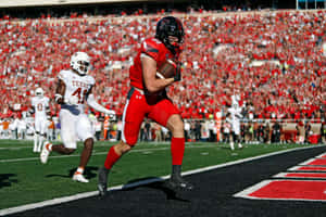 A Football Player Running With The Ball In His Hands Wallpaper