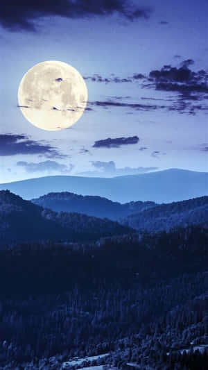 A Full Moon Rising Over A Mountain Wallpaper